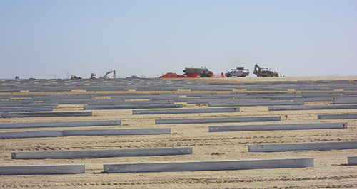 Photo 10. Pile layout starts with electrical vault excavation (in the distance). 