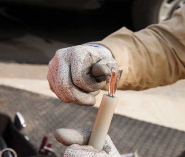 Photo 2. Lineman fans strands of conductor in preparation of electrical cable fluid injection procedure.