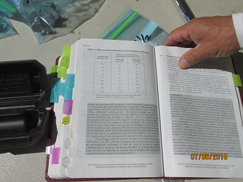 Photo 9F. Special inspector is verifying appropriate values (Kips) for Pre-Installation Verification. Notice all the homemade tabs identifying sections of the AISC Manual. This is the special inspector’s bible. Without this reference in the field, the inspector cannot perform his or her job. Look for it next time you’re out at any large steel construction project.