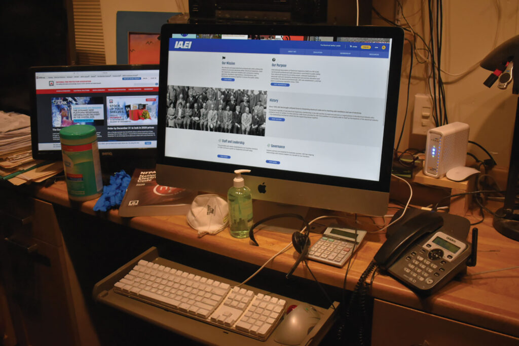 Photo 1. A well-equipped inspector workstation with large and smaller monitors, telecommunication equipment, NIOSH N95 face mask, hand sanitizer, disinfecting wipes, and nitrile gloves.  Courtesy of John Wiles