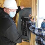 Ulster BOCES Electrical Construction & Maintenance students from Saugerties Central School District, Jonathan Toth (left) and Kaitlyn Lennon work together to hang the electrical panel at the Habitat for Humanity house in Glasco, NY. Photo Courtesy-Kristine Conte/Ulster BOCES