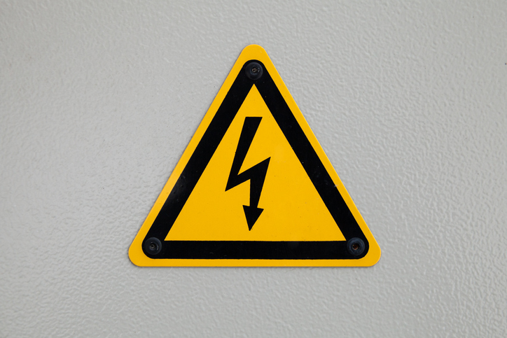 High voltage triangle warning sign mounted on gray metal wall